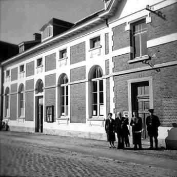 Zwartwit foto van het oude vredegerecht van Herne met 4 personen voor de inkomdeur