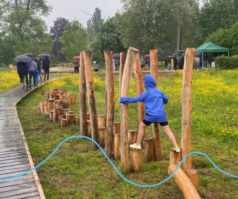 Kind met blauwe jas lopend over het boomstammenparcours